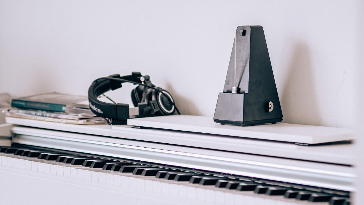 white piano with metronome standing on top of it